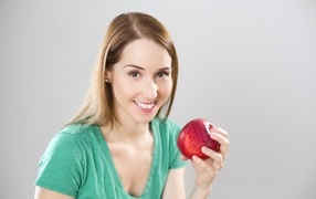 Красивая улыбающаяся девушка с яблоком в руках 