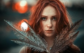 Яркая рыжеволосая девушка с перьями в руках