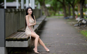 Милая девушка азиатка сидит на лавке