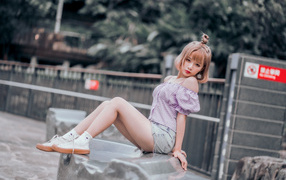 Милая девушка азиатка сидит на камне