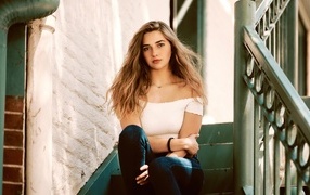 Милая девушка брюнетка сидит на ступеньках