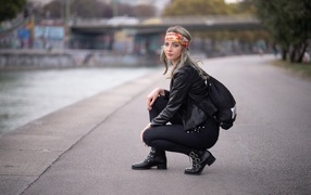 Девушка в черном костюме сидит на корточках