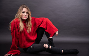 Girl in a red sweater sits on a gray background