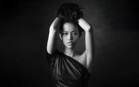 Девушка модель с руками в волосах  у стены