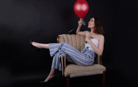 Девушка с шариком и розой сидит в кресле