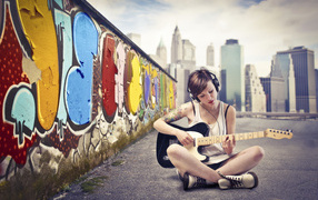 Девушка с гитарой сидит у стены