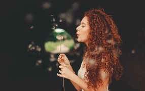 Red-haired girl with a dandelion in her hand