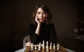 Умная молодая девушка играет в шахматы