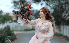 Smiling Asian girl in a pink dress with a bouquet