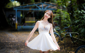 Улыбающаяся азиатка в белом платье в парке