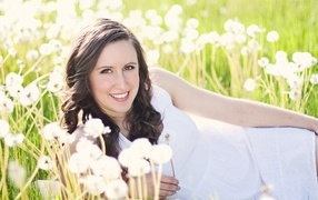 Улыбающаяся девушка лежит на поле с одуванчиками