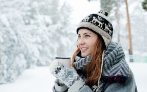 Улыбающаяся девушка с чашкой кофе зимой