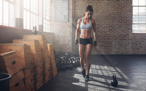 Спортивная девушка в спортзале с гирями