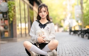 Молодая девушка азиатка сидит в позе лотоса на дороге