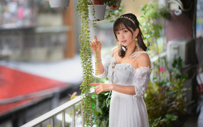 Young Asian woman in white dress near the plants