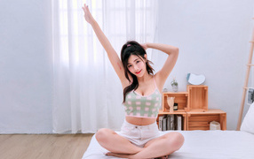 Молодая азиатка сидит на кровати утром