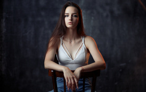 Young long-haired girl sitting on a wooden chair