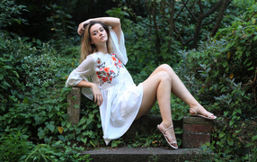 Молодая женщина в белом платье в парке