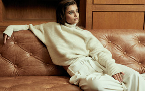 Model Taylor Hill in a white suit sits on the sofa