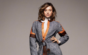 Stylish young model Miranda Kerr in a coat on a gray background