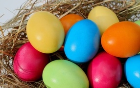Много разноцветных пасхальных яиц в гнезде
