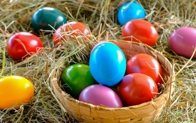 Multi-colored Easter eggs in a basket on hay