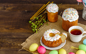 Sweet Easter cakes on the table with tea and colored eggs