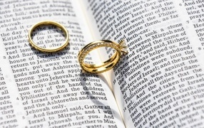 Two gold wedding rings lie on a newspaper
