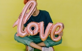 A man holds balloons with the inscription love