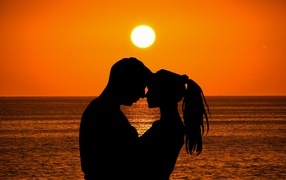 Влюбленная пара на закате солнца у моря
