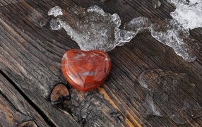 Сердце из камня на деревянной лавке с тающим снегом