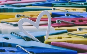 Белое деревянное сердце с разноцветными прищепками