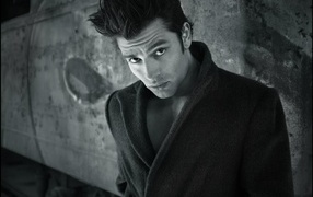 Красивый мужчина в черном пальто у стены