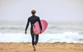 Мужчина серфингист идет к морю