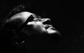 Man with glasses looking up on a black background