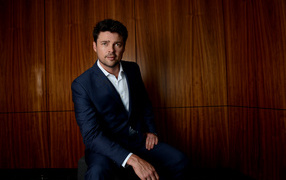 Актер Карл Урбан в костюме на фоне стены