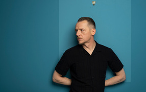 Actor Simon Pegg standing against a wall