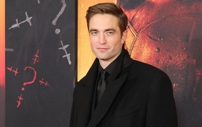 Popular actor Robert Pattinson in a suit stands against the wall