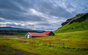 Дом у покрытой зеленью поры под грозовым небом