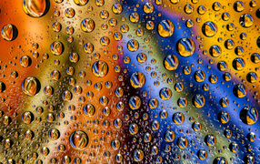 Капли воды на разноцветном стеклянном фоне