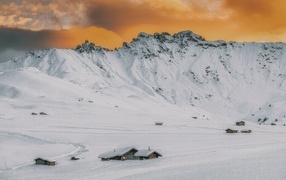 Красивая заснеженная гора под оранжевым небом