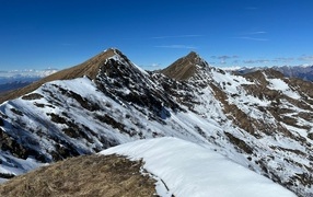 Снег лежит на вершинах гор под голубым небом