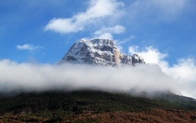Snowy mountain peak in white clouds