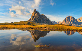 Доломитовые Альпы отражаются в озере под голубым небом