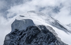 View of a snow-capped mountain peak under white clouds