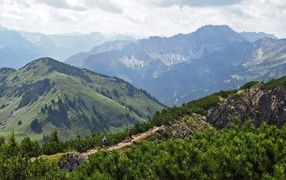 Вид на высокие покрытые зеленью горы под белыми облаками