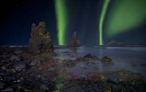 Northern lights over water with big stones