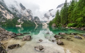 Камни лежат в воде озера в холодных горах