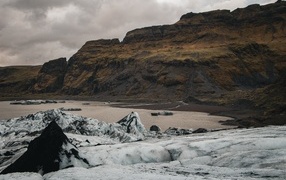 Холодный грязный снег на берегу моря у гор 