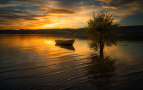 Лодка в воде спокойного озера на закате солнца